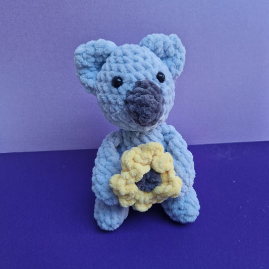 Crochet chunky, super soft blue and grey glittery sitting koala with a sunflower