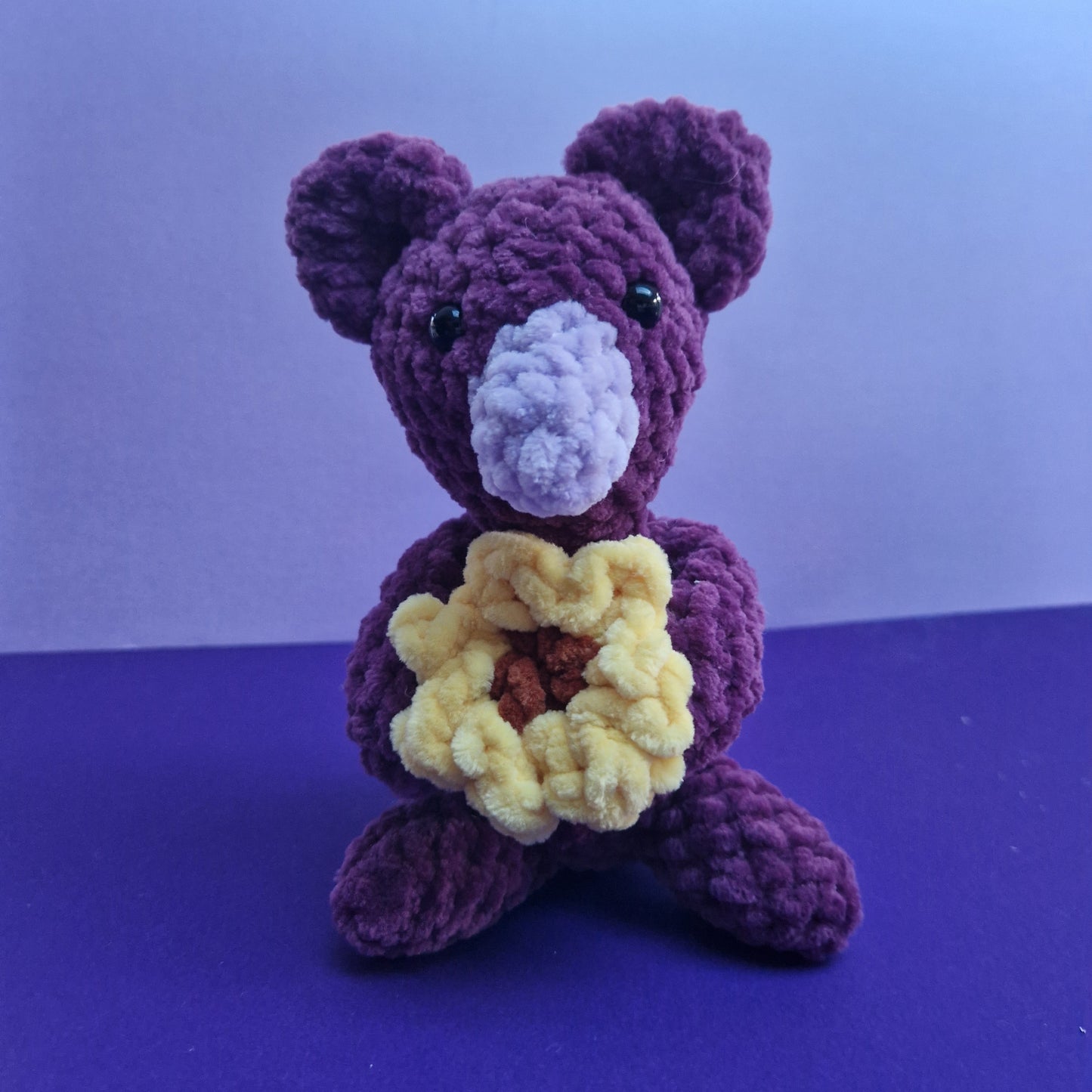 Chunky, super soft purple koala holding a sunflower