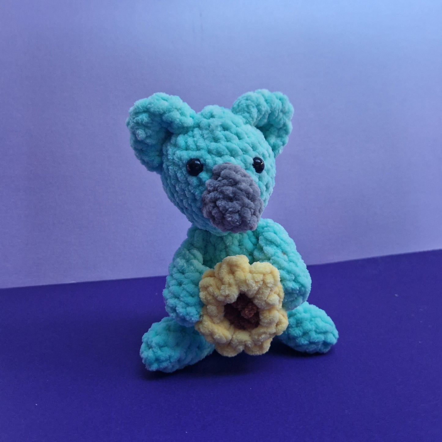 Chunky, super soft mint green koala holding a sunflower