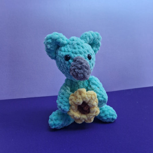 Chunky, super soft mint green koala holding a sunflower